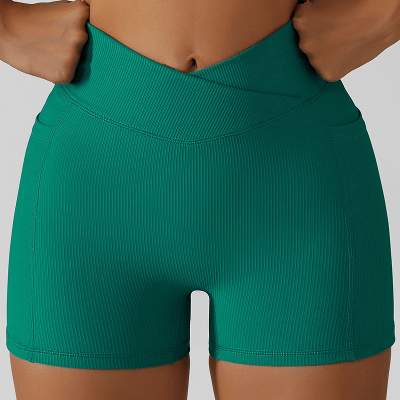 Stylish elastic women's shorts in green with side pockets, perfect for yoga, crafted from quick-dry, breathable nylon. Model wearing shorts.